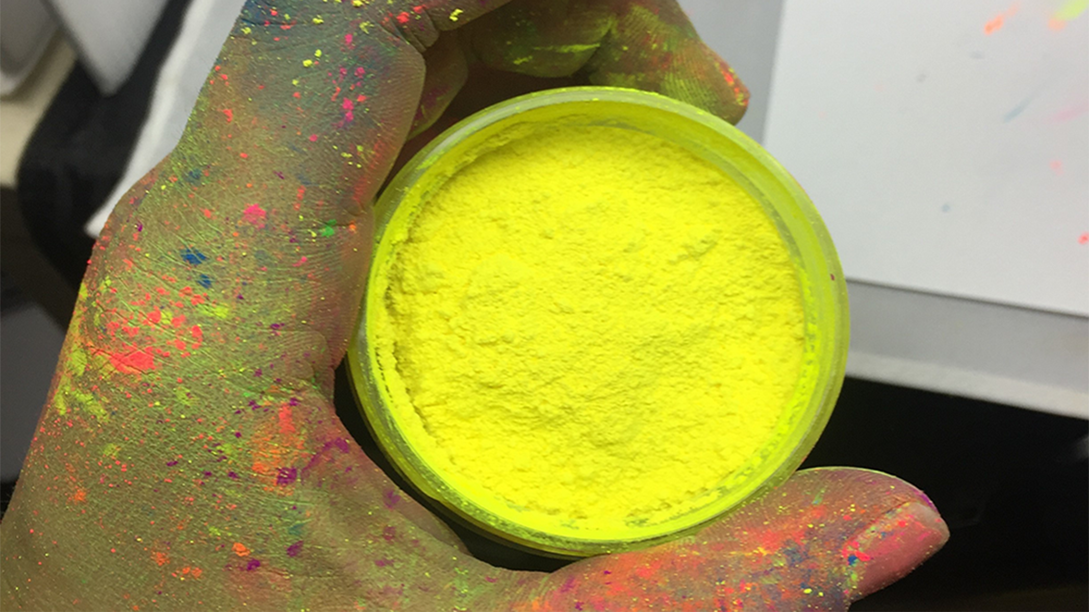 hand holding container of Saturn Yellow fluorescent pigment 